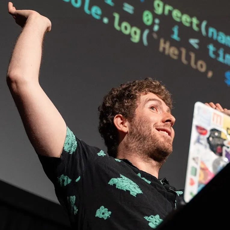 Me raising hands happily while giving a talk on stage, with code projected behind me